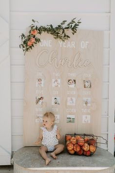 a baby sitting on a table next to a sign that says one year of carrots