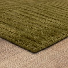 a close up view of a green rug on a wooden floor with wood grained surface