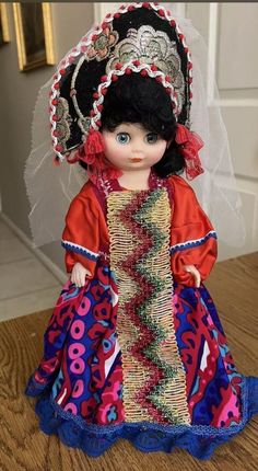 a doll is wearing a colorful dress and headdress with a veil on it