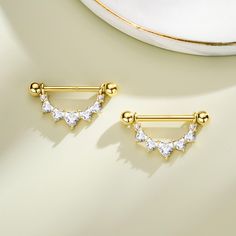 two pairs of gold plated earrings with clear stones on them, sitting next to a white plate