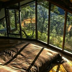 a bed sitting in the middle of a room with lots of windows on top of it