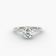 a white gold engagement ring with diamonds on the band and a round brilliant center stone