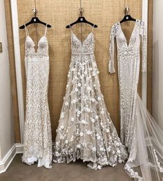 three dresses hanging up in front of a wall