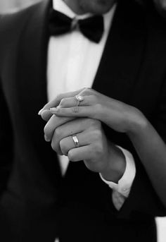 a man in a tuxedo holding the hand of a woman wearing a wedding ring