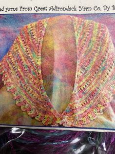 an image of a knitted shawl in pink, yellow and green colors on a purple background