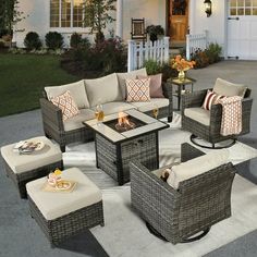 an outdoor living room with wicker furniture and fire pit in front of a house