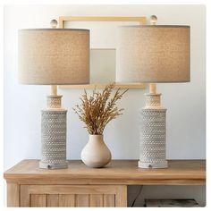 two lamps sitting on top of a table next to a vase with flowers in it