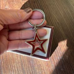 a hand holding a red and white star shaped keychain