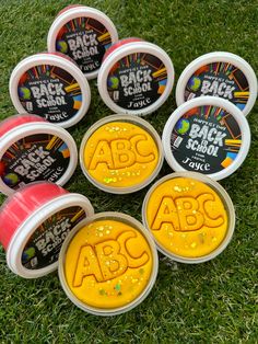 the abc's ice creams are in plastic containers on the grass with letters painted on them