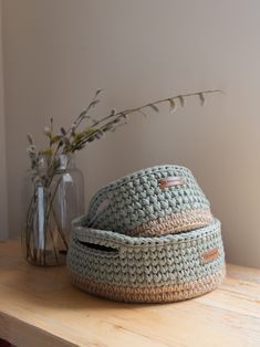 a crocheted hat sitting on top of a wooden table next to a vase