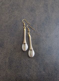 Cowrie shell and gold wire dangle earrings White Brass Earrings For Beach, White Brass Earrings For The Beach, Gold Teardrop Earrings For The Beach, Gold Dangle Earrings For Beach, Beach Brass Dangle Earrings, Gold Shell Dangle Earrings, Gold Beaded Earrings For Beach, Gold Shell-shaped Metal Earrings, Gold Shell-shaped Brass Earrings