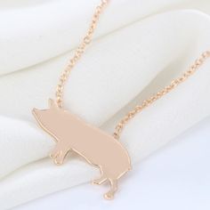 a gold necklace with a small fox on it's side, sitting on top of a white cloth