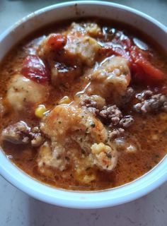 a bowl of soup with meat and vegetables in it sitting on a white counter top