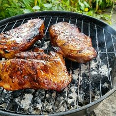 three pieces of meat cooking on a grill