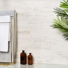 two brown bottles are next to a towel rack on a marble countertop in front of a white tiled wall