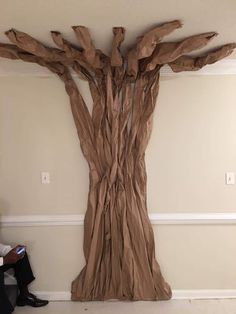 a man sitting in front of a tree made out of cardboard