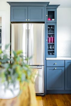 a kitchen with blue cabinetry and stainless steel refrigerator freezer, wood flooring