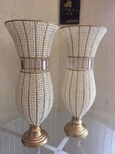 two white vases sitting on top of a glass table next to a wall hanging