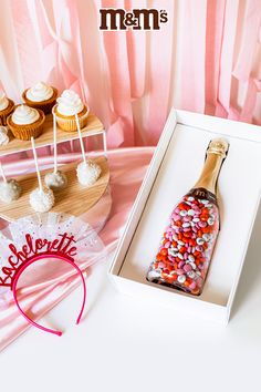 a bottle filled with lots of candy next to cupcakes