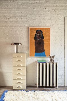 a white radiator in front of a brick wall with a painting on it