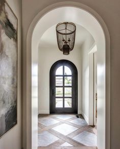 an archway leading into a foyer with a black door and large painting on the wall