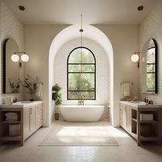 a large white bathtub sitting under a window in a bathroom next to two sinks