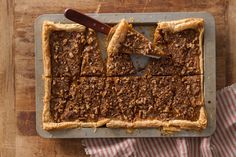 an overhead view of a pie on a wooden table with a knife and napkin next to it