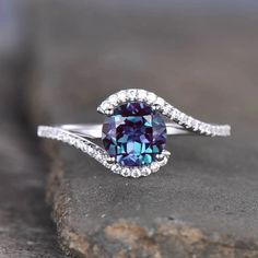 a blue and white diamond ring sitting on top of a rock