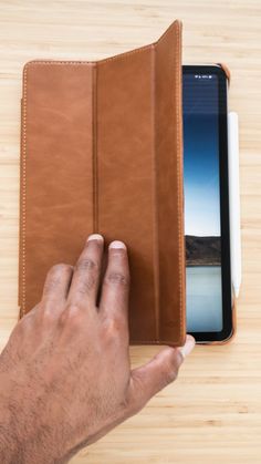 a hand holding an ipad case on top of a wooden table