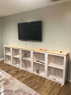 a flat screen tv mounted on top of a wooden entertainment center in a living room