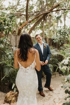 a man in a blue suit standing next to a woman in a white dress