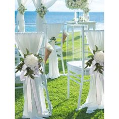 the chairs are decorated with white flowers and ribbons for an outdoor wedding ceremony at the beach