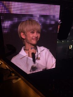 a young boy holding a microphone in front of a screen with the image of himself on it