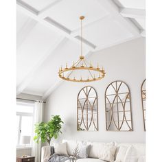 a living room with white couches and mirrors on the wall above them, along with a potted plant