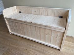 a wooden bench sitting on top of a hard wood floor next to a white wall