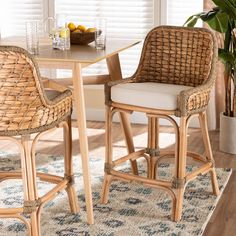 two wicker bar stools sitting on top of a rug next to a table