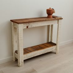 a wooden table sitting on top of a hard wood floor next to a white wall