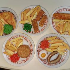 four plates filled with different types of food on top of a white countertop next to each other