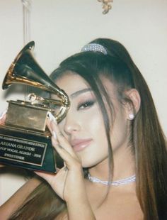 the woman is holding up her award for best performance in a musical instrument, and posing with it's hands on her face