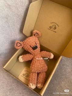 a brown teddy bear sitting inside of a box