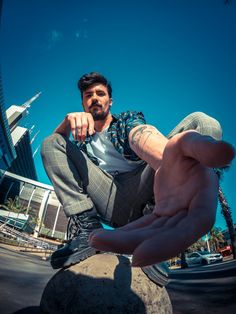 a man sitting on top of a rock next to a hand