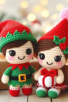 two small crocheted dolls sitting next to each other on a wooden table in front of a christmas tree