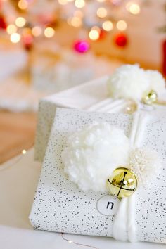 a present wrapped in white paper with pom - poms on it sitting on a table