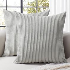 two white pillows sitting on top of a couch