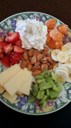 a plate full of fruit, nuts and cheese on top of a floral design plate