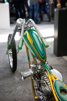 a green and yellow motorcycle parked on top of a cement floor next to a building