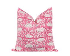 a pink pillow with white flowers and leaves on the front, sitting against a white background