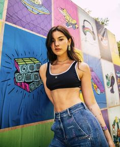 a beautiful young woman standing next to a colorful wall