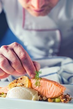 a chef is preparing food on a white plate