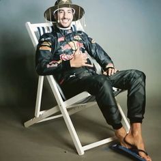 a man sitting in a chair with a hat on his head and sandals under his feet